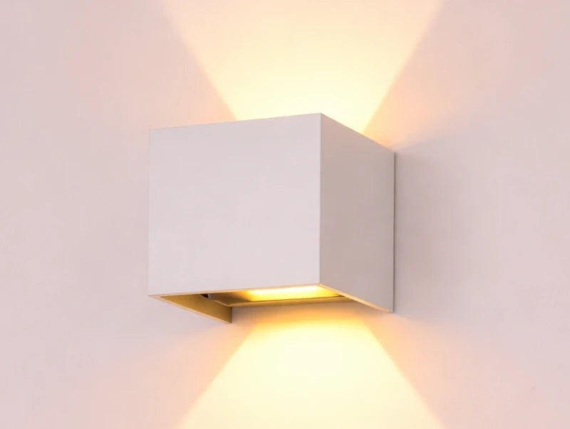 מנורת קיר CUBINA בצבע לבן מאירה על הקיר