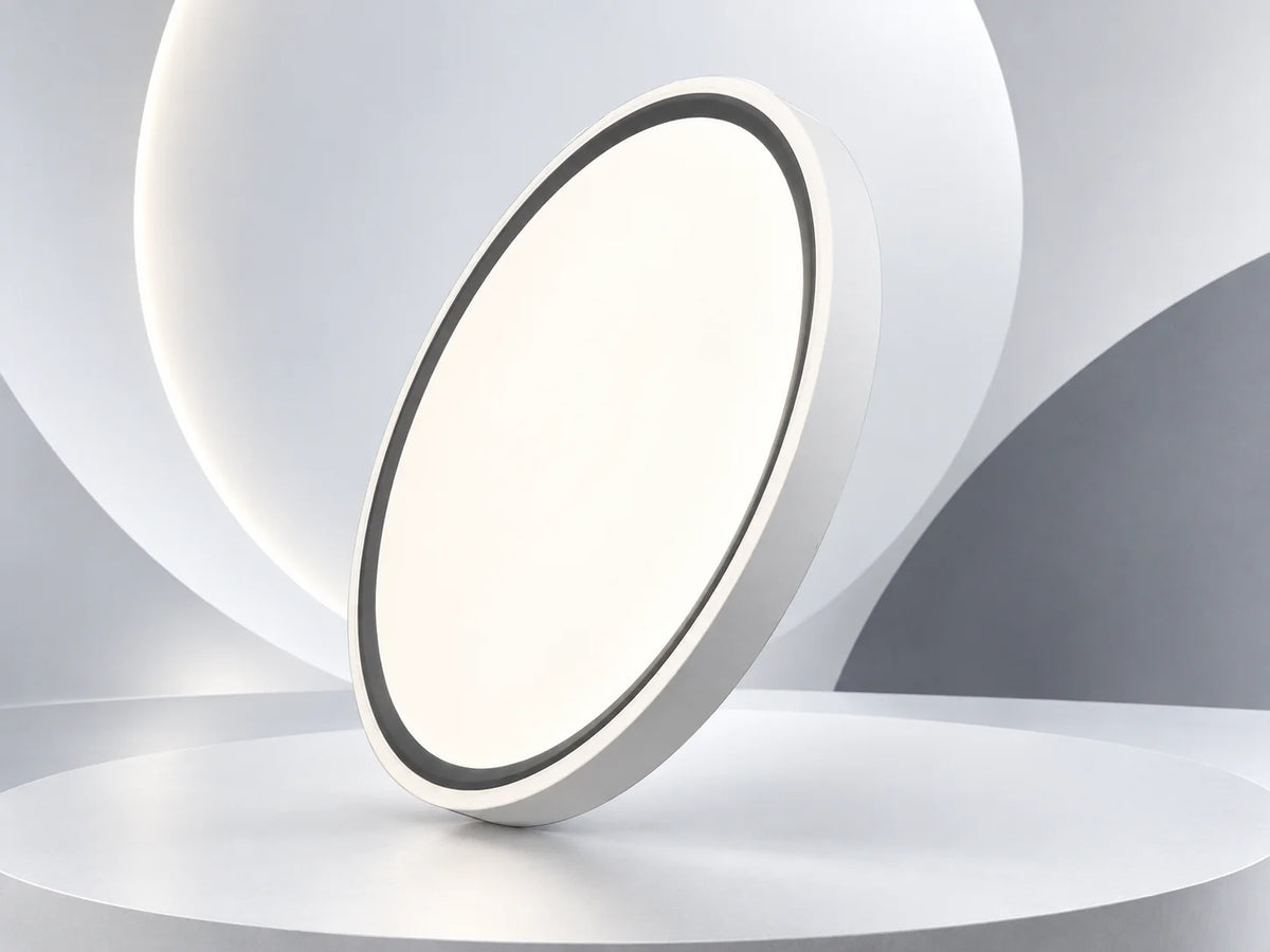 גוף תאורה צמוד תקרה OMEGA RING CCT עגול לבן עם מסגרת שחורה על רקע אבסטרקטי בהיר.