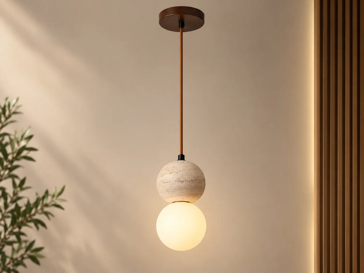 גוף תאורה תלוי דגם SFERA של OMEGA, עם חלק עליון כדורי טרוורטין וחלק תחתון כדורי זכוכית חלבית מוארת, על רקע קיר בהיר.