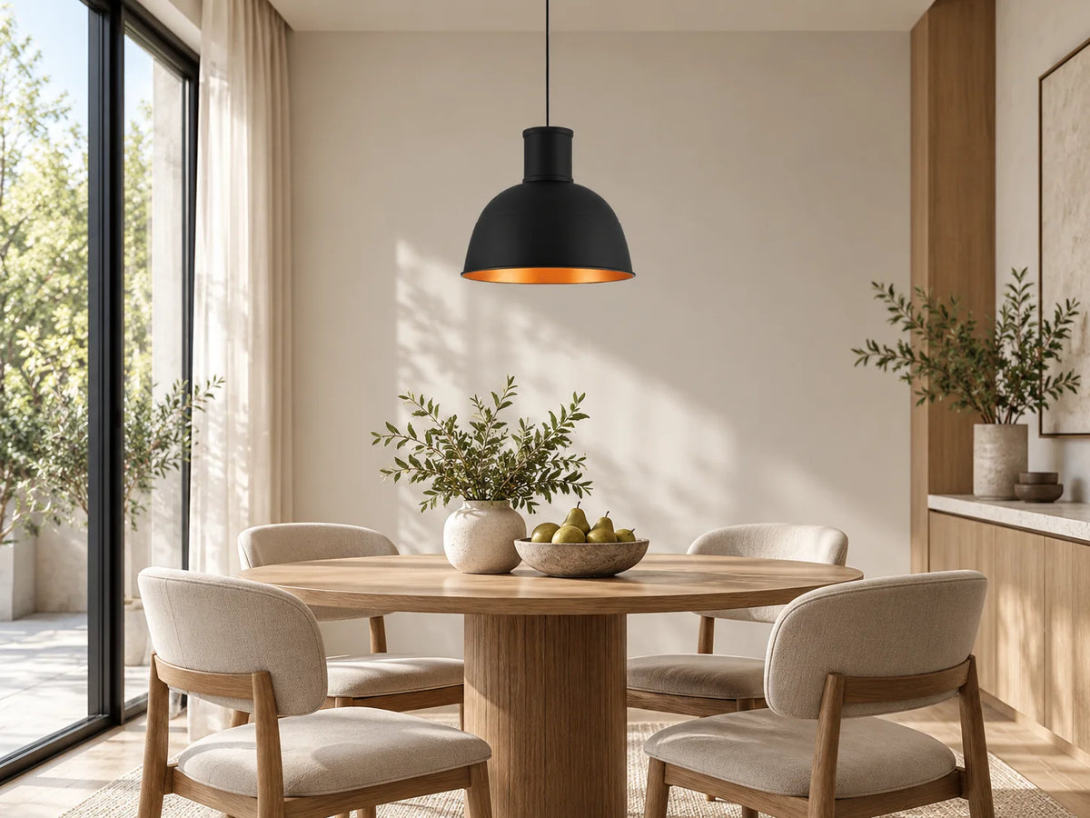 מנורת תליה שחורה MONOLI של SEMICOM עם פנים נחושת תלויה מעל שולחן אוכל מעץ בחדר מודרני.